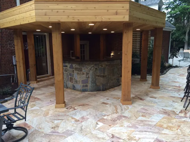 Cedar pavilion with recessed lights over a stone-faced outdoor bar on a flagstone patio